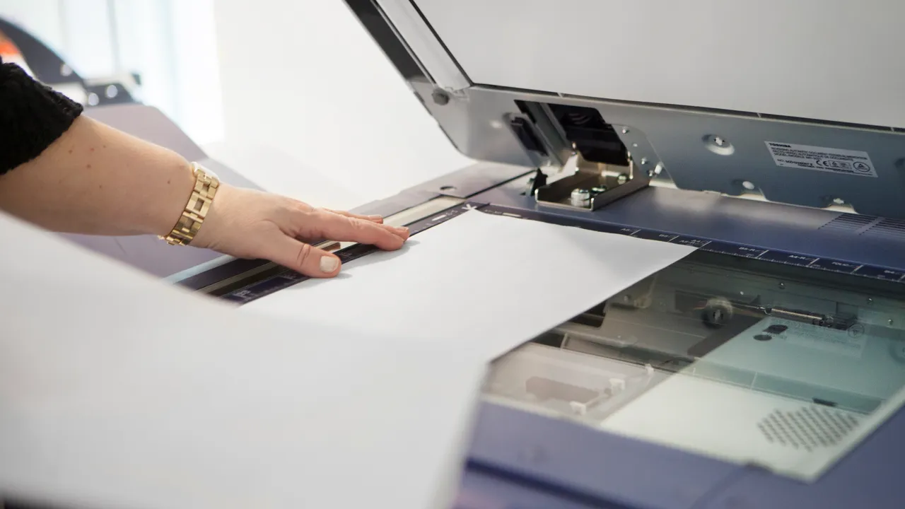 En närbild på en kopiator som används av en person.