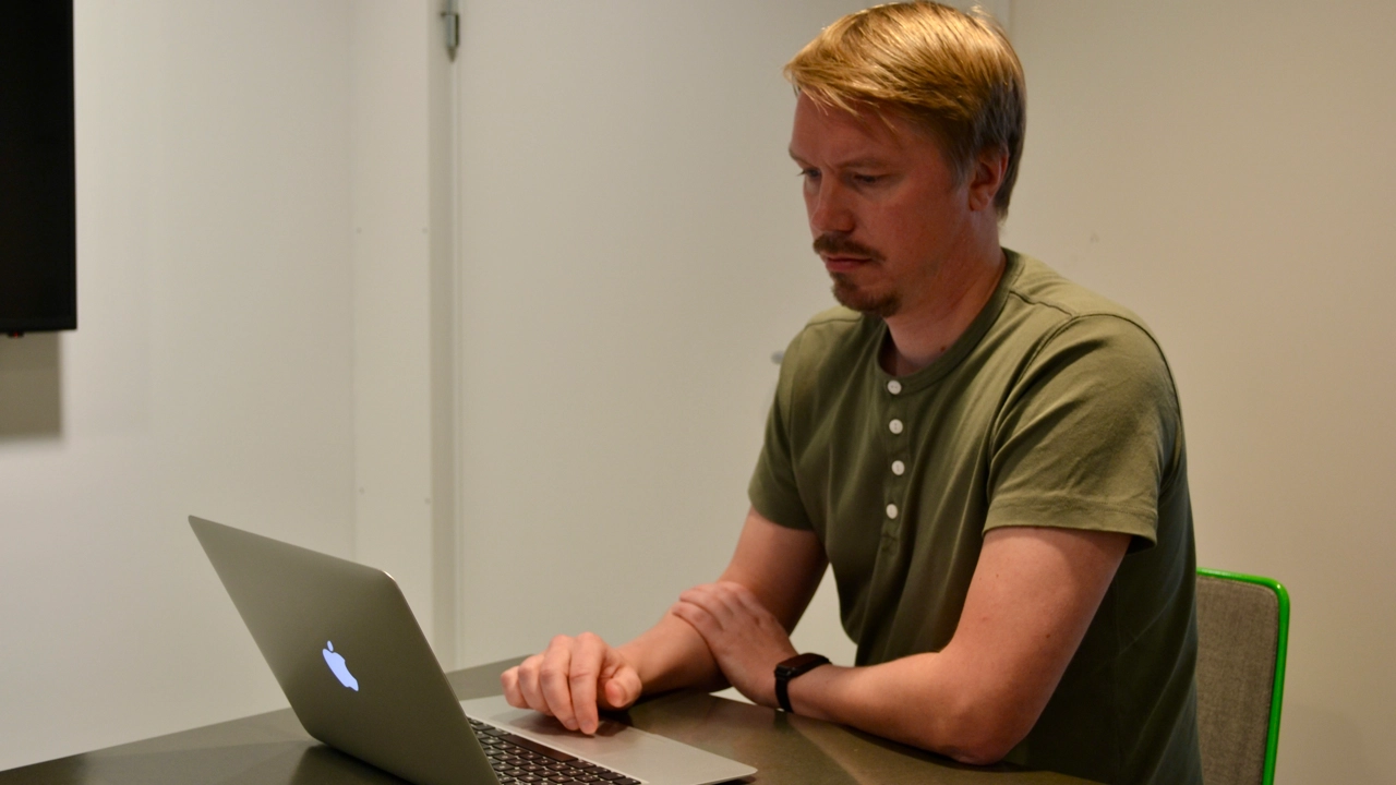 Bild på Kristoffer Bylund vid skrivbord med laptop framför sig