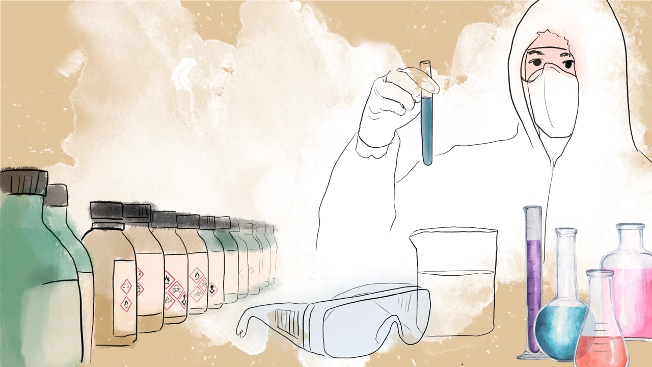 Person with protective clothing holding a test tube with lab bottles in the background.