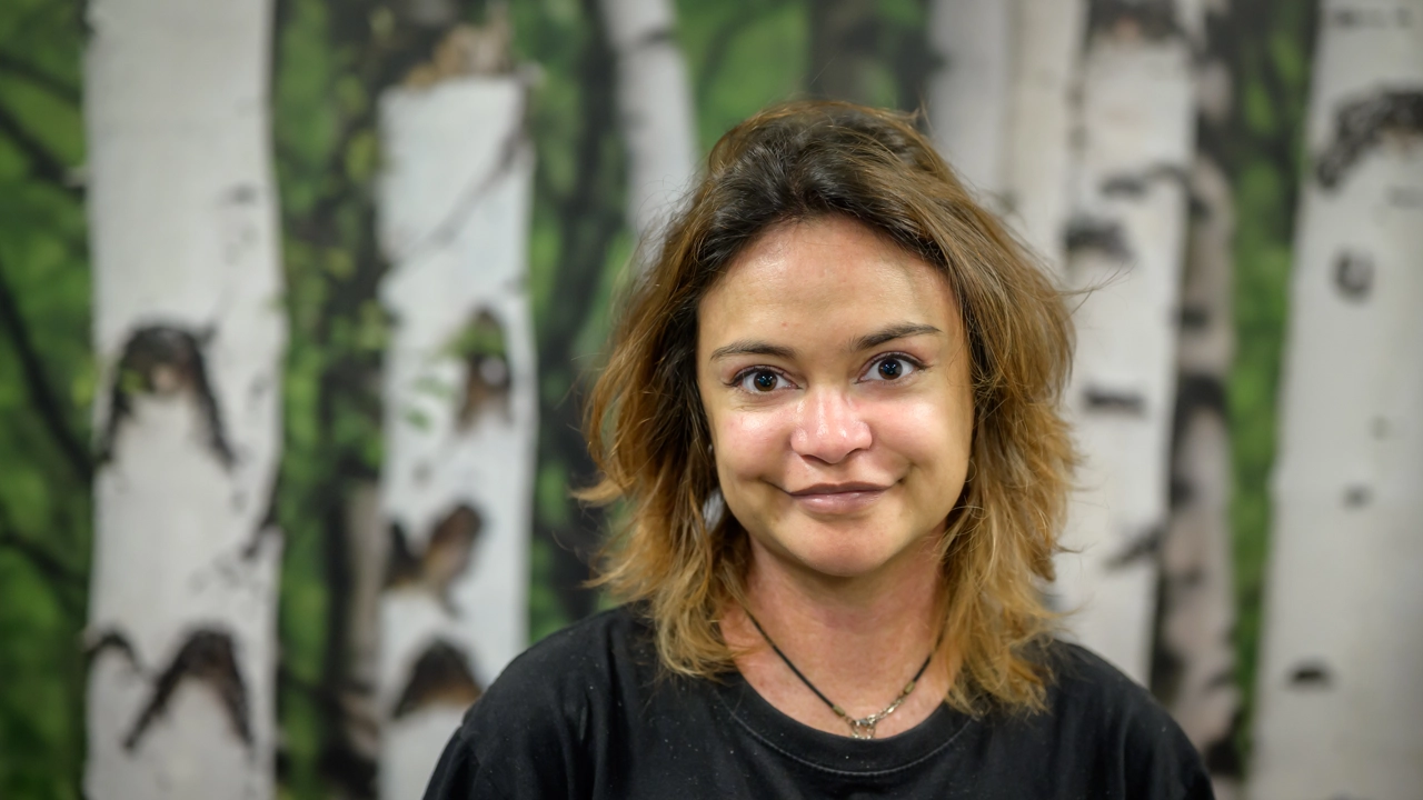 A woman standing in front of a painting of trees