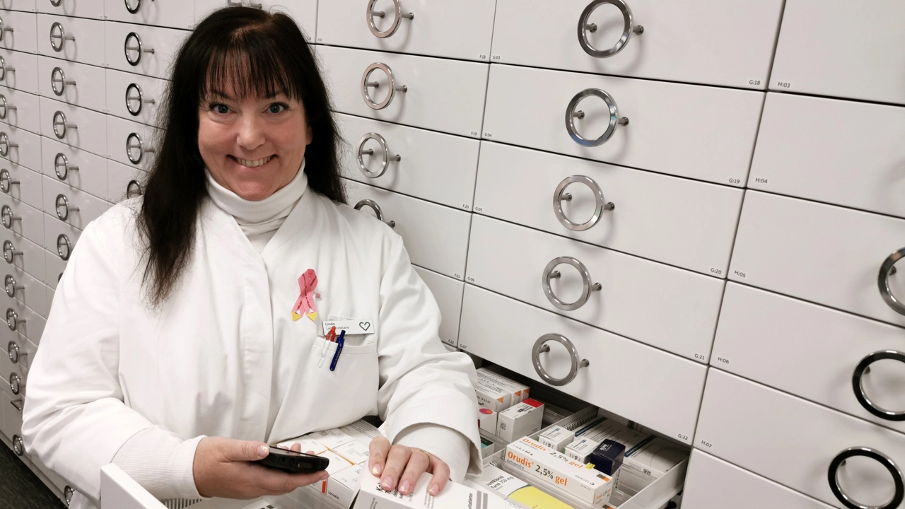 Bild på receptarien Lindha Lydahl i vit rock vid lådor med läkemedel ett apotek
