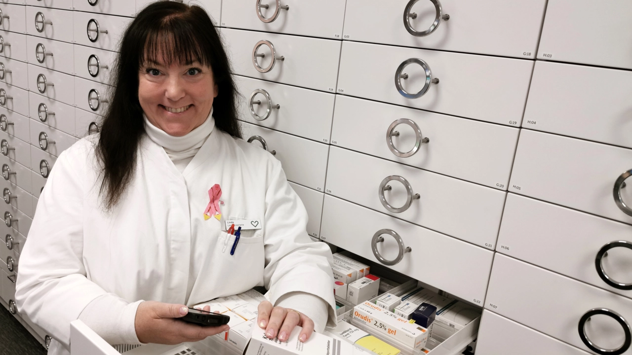 Bild på receptarien Lindha Lydahl i vit rock vid utdragbara lådor med läkemedel på ett apotek