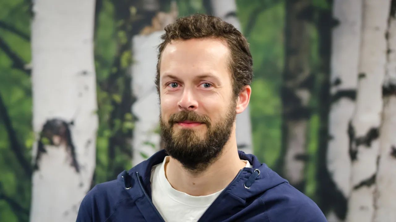 A man with a beard standing in front of a painting