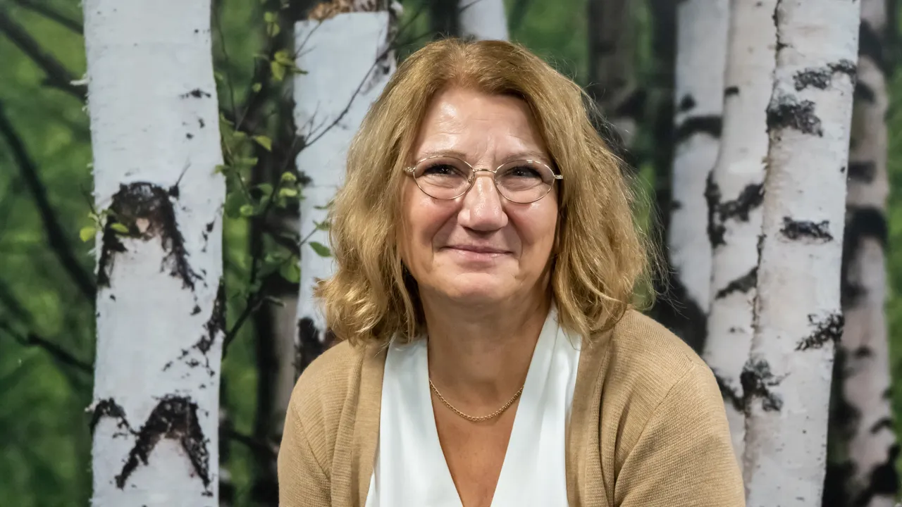 A woman sitting in front of a painting of trees