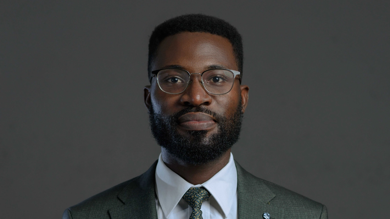 Michael Oghenetega Abu in a suit and tie posing for a picture.
