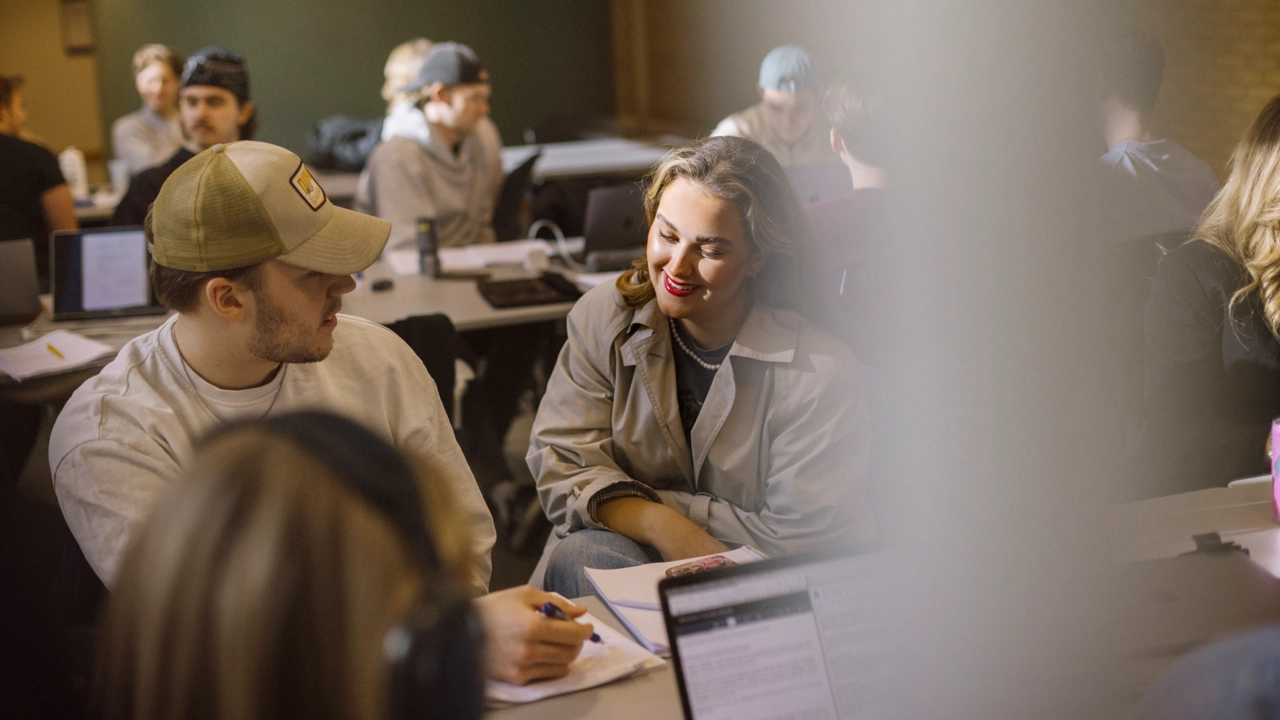 Nöjda studenter pratar med varandra i ett klassrum.