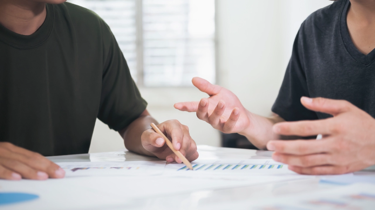 Två personer samtalar med projektunderlag framför sig på bordet.