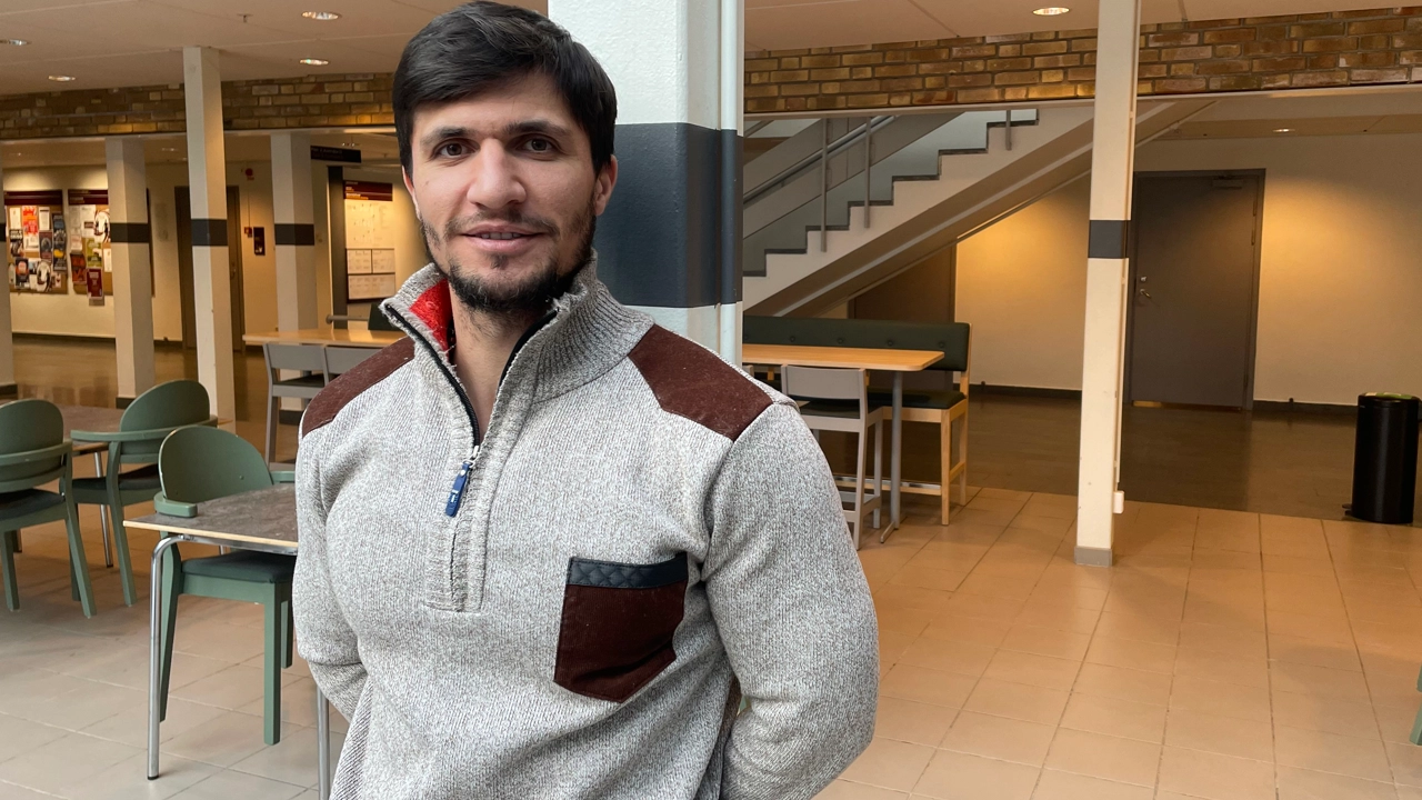 Bild på Najmaalddin Saifaddin Dawoud stående i undervisningslokal med bord och stolar