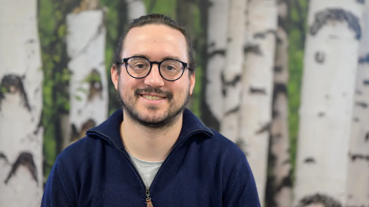 A man wearing glasses standing in front of a painting
