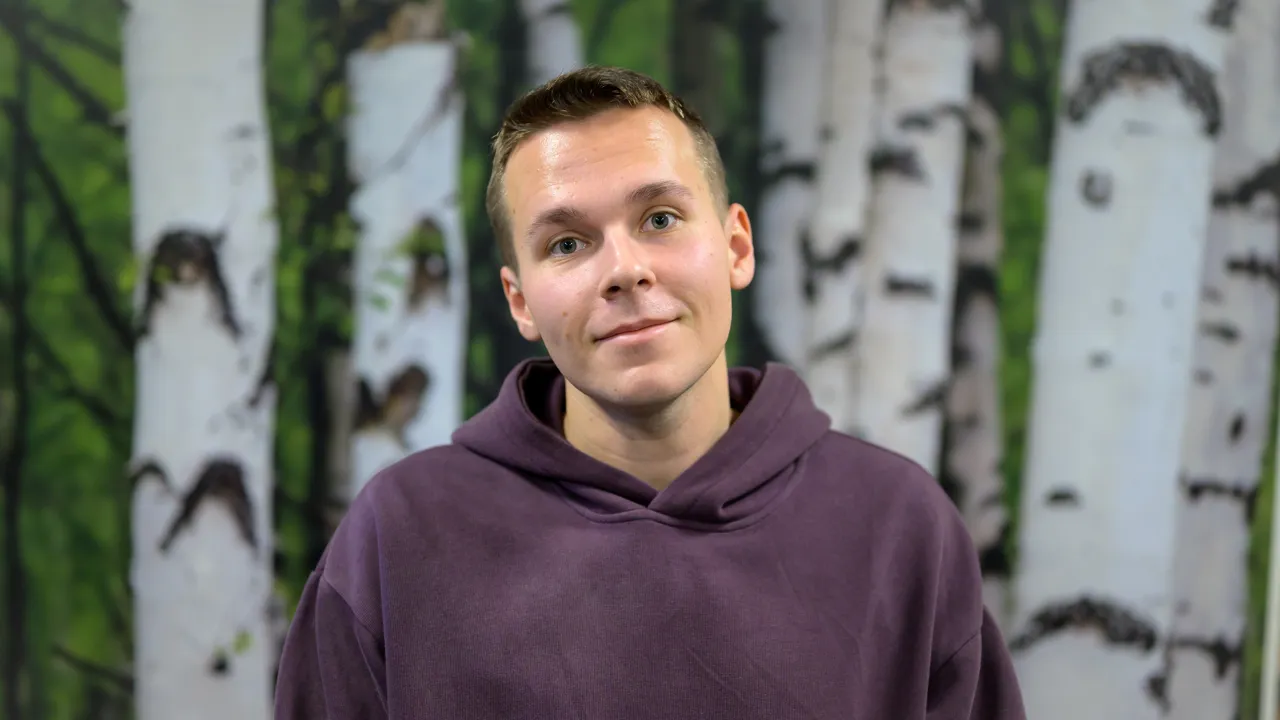 A man standing in front of a painting of trees