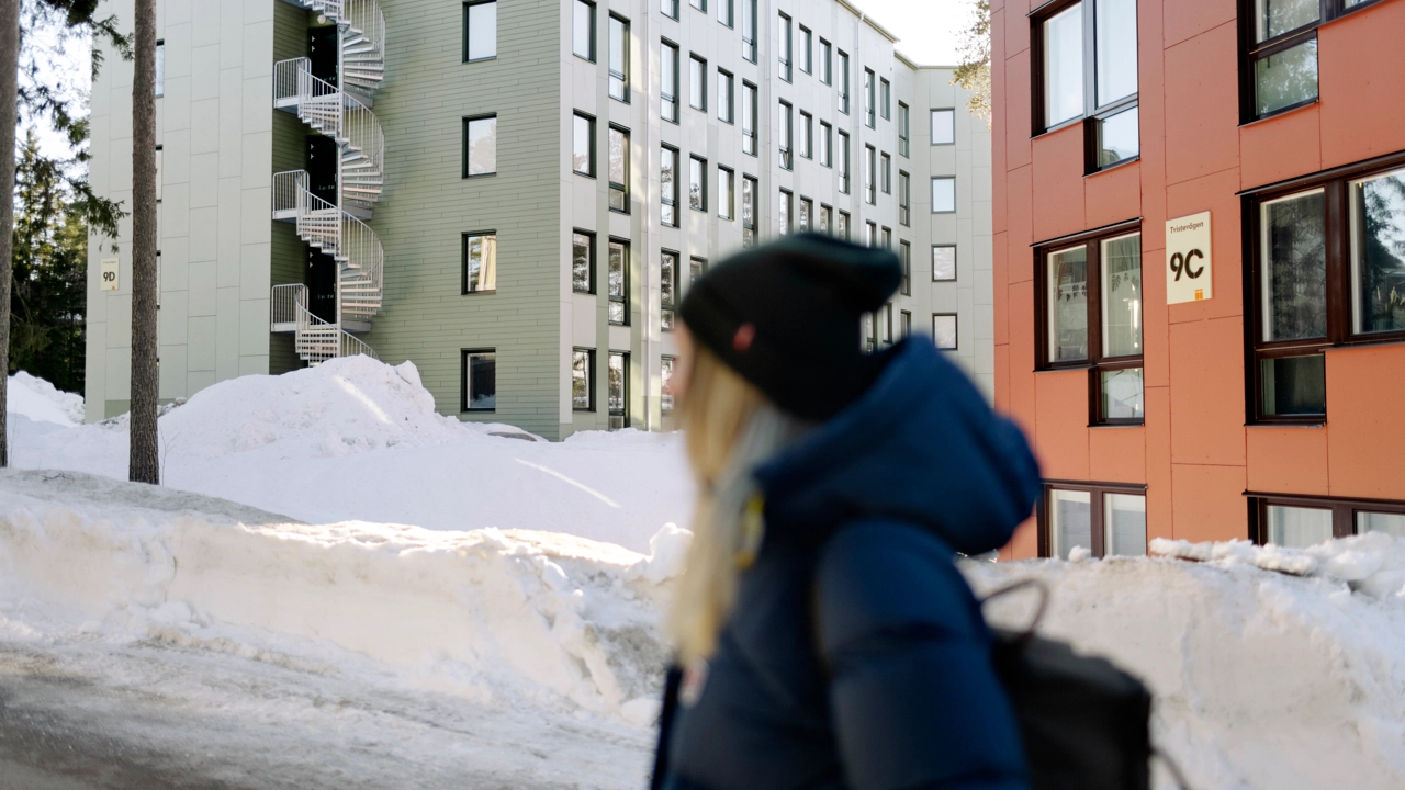 A blurred person is walking home among residential buildings in a wintery Umeå.