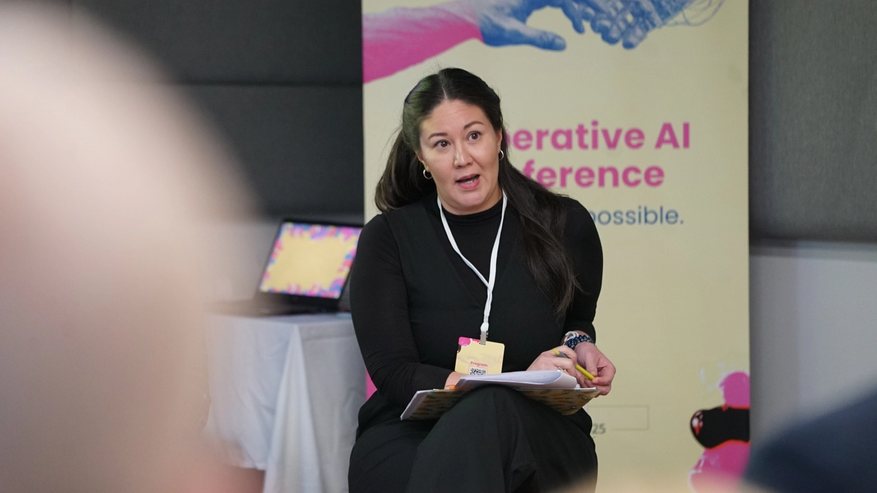 A woman presenting at a conference sitting in a chair.