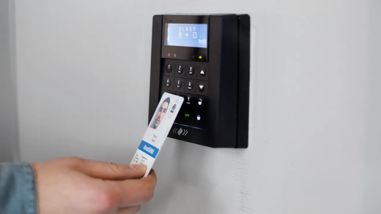 A hand holds a card to a card reader.