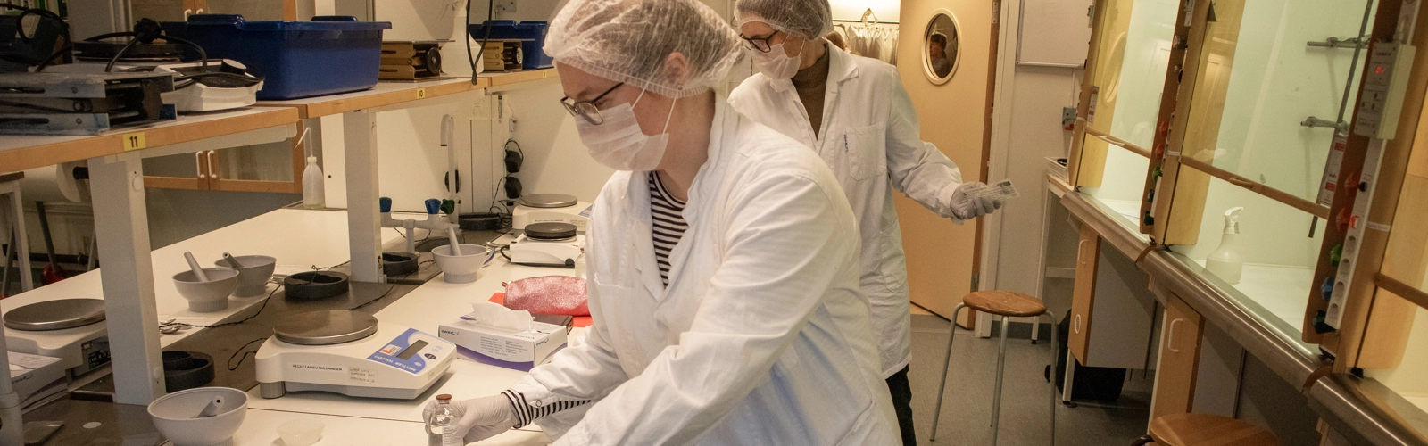 Bild på receptariestudenter med munskydd och mössor som förbereder laboration.