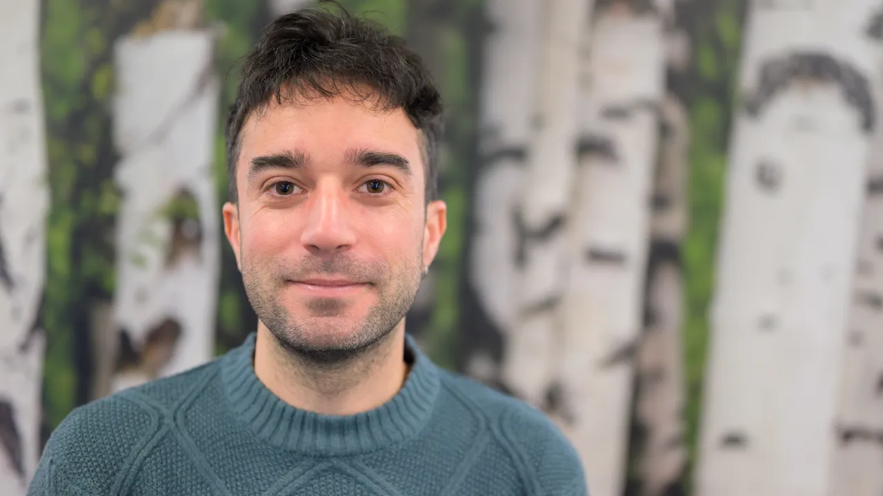 A man standing in front of a painting of birch trees