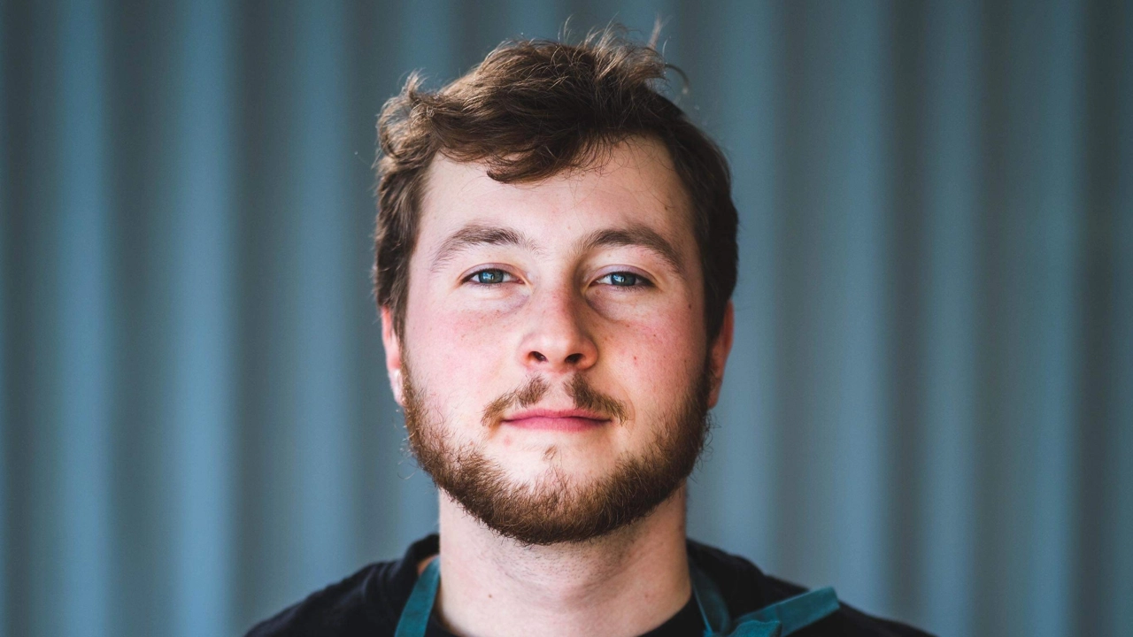 En man med skägg som bär ett förkläde.