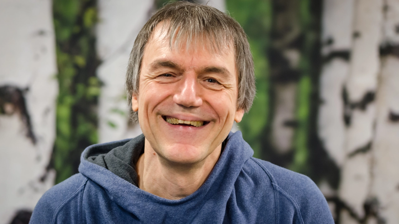 A man in a blue hoodie smiles at the camera