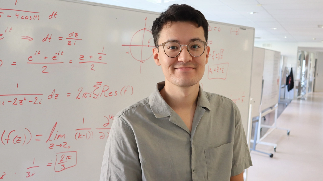 Porträttbild på Shohruh Tohirov, i bakgrunden whiteboardtavla med matematiska beräkningar