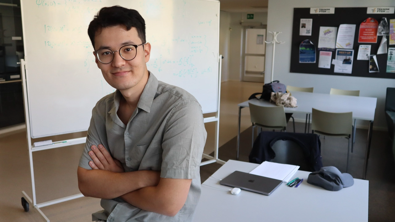 Bild på Shohruh Tohirov, i bakgrunden en whiteboardtavla i teknisk fysiks korridor