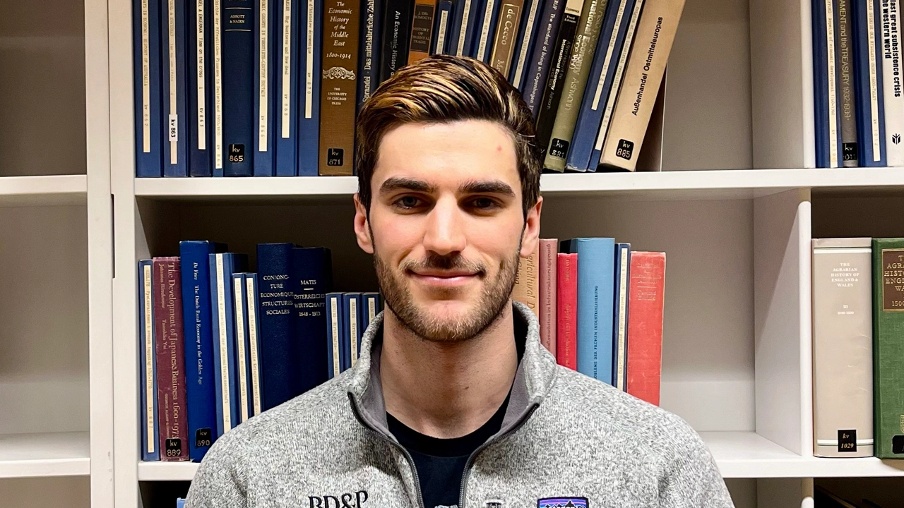 Portrait of Simon in front of a bookshelf.