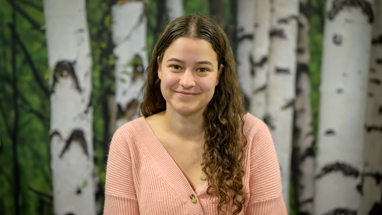A woman standing in front of a painting of trees