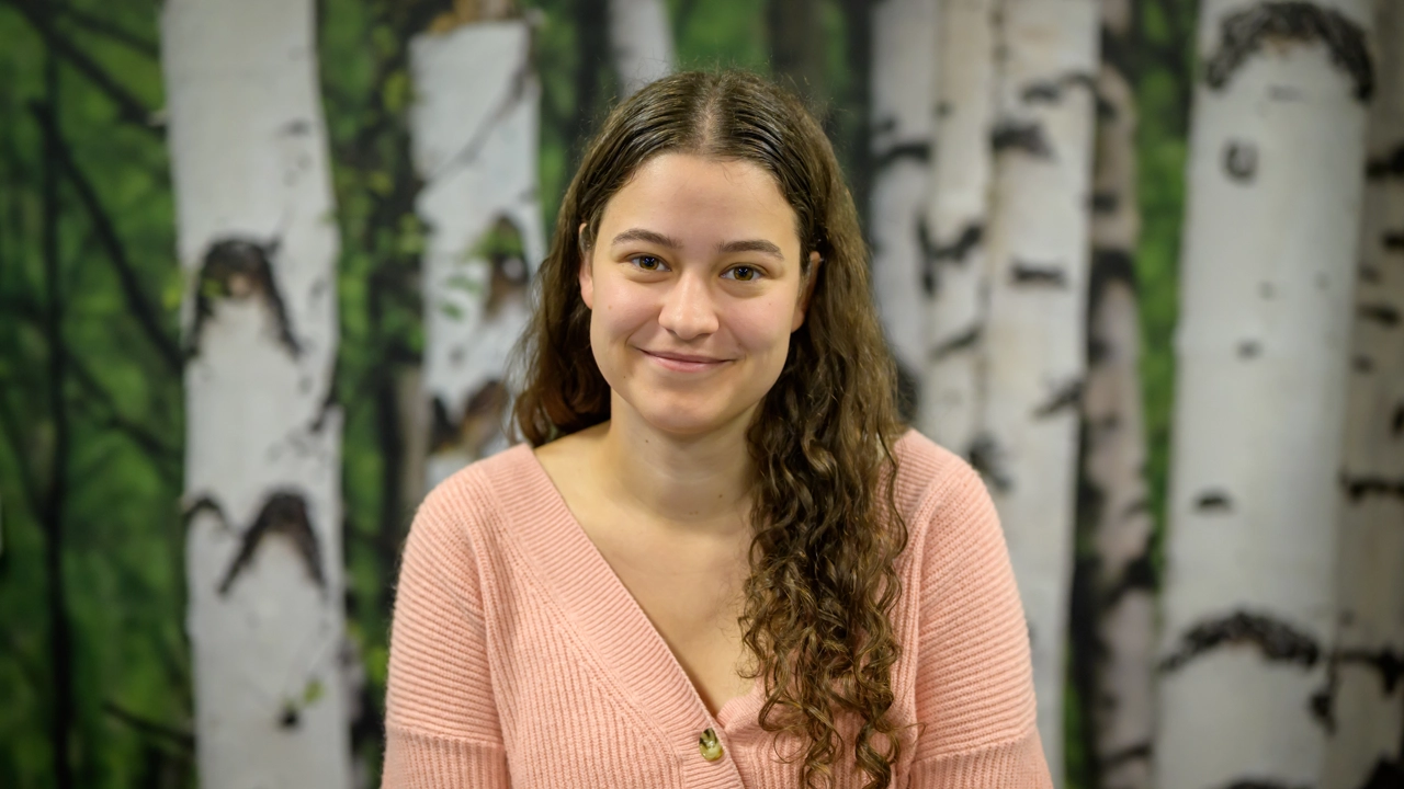 En kvinna står framför en målning med träd