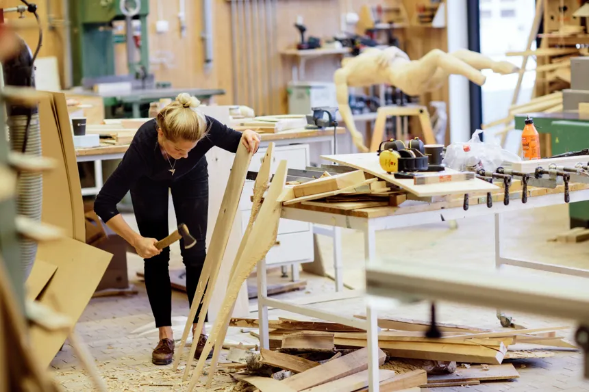 En student på Konsthögskolan är i en ateljé och jobbar med sitt konstverk i trä.