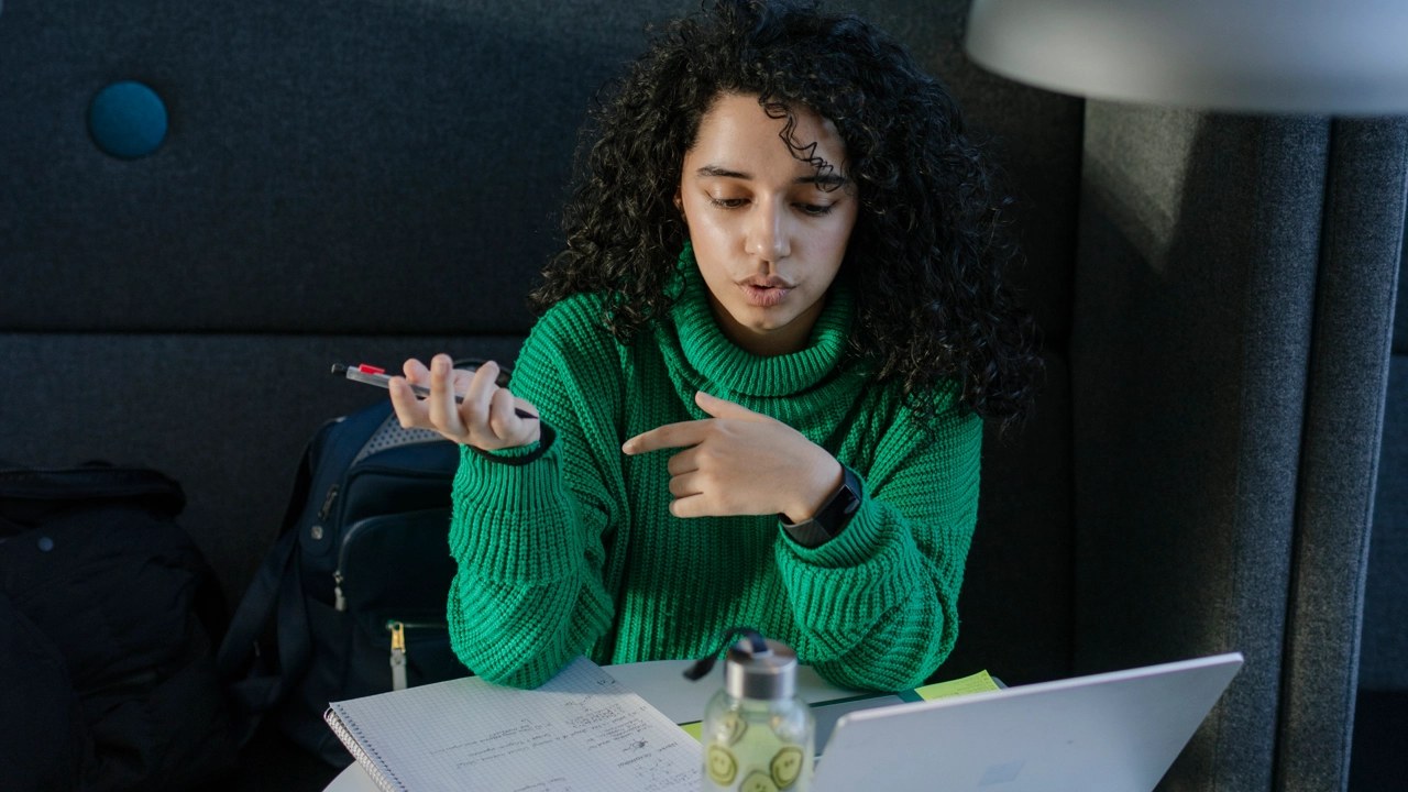 Studenten Sarah pluggar med dator och anteckningsblock.