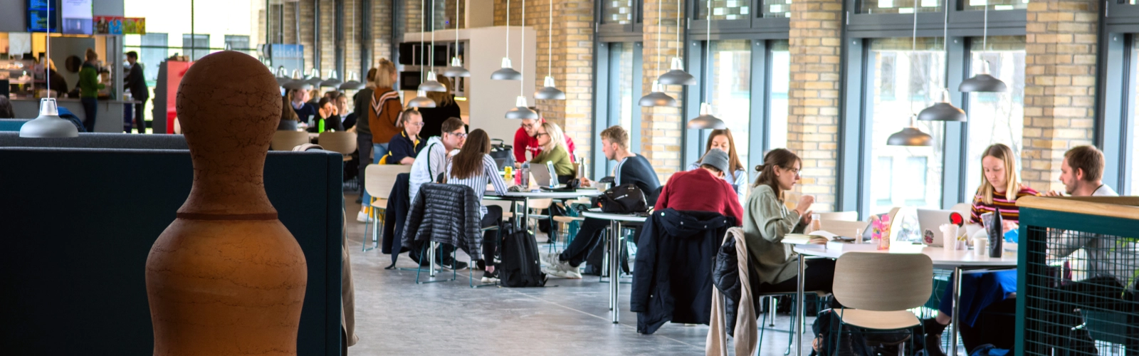 En grupp människor som sitter vid bord i ett stort rum.