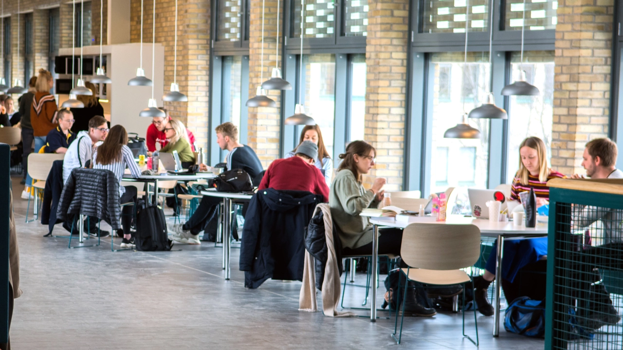 En grupp människor som sitter vid bord i ett stort rum.