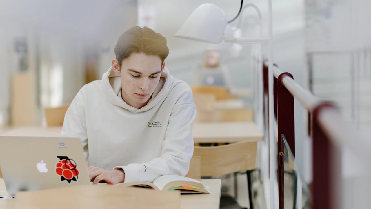 Studenten Hugo pluggar med dator och anteckningsblock.
