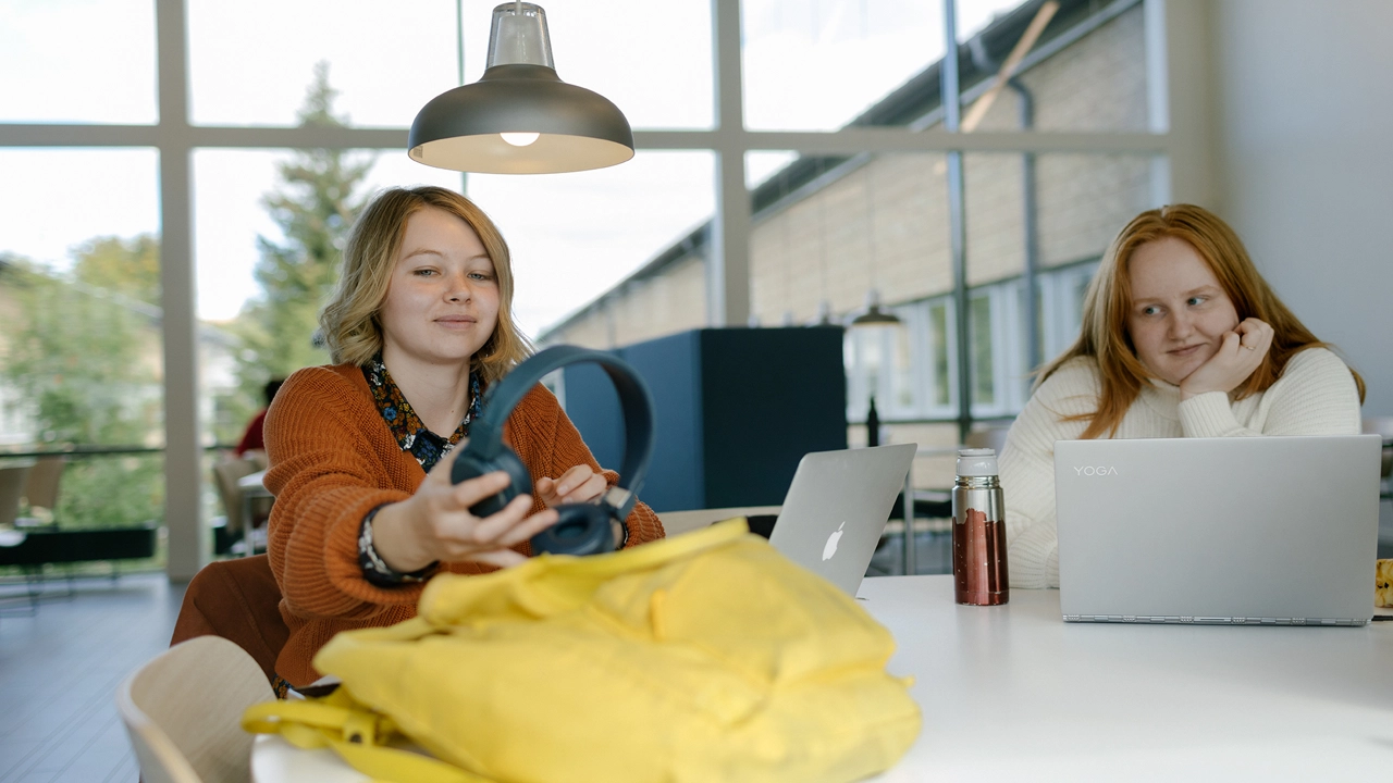 Två kvinnliga studenter sitter i Humanisthuset och pluggar. 