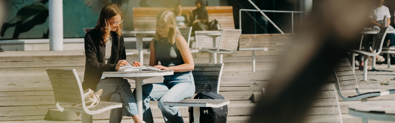 Två kvinnor sitter vid ett bord och pratar.