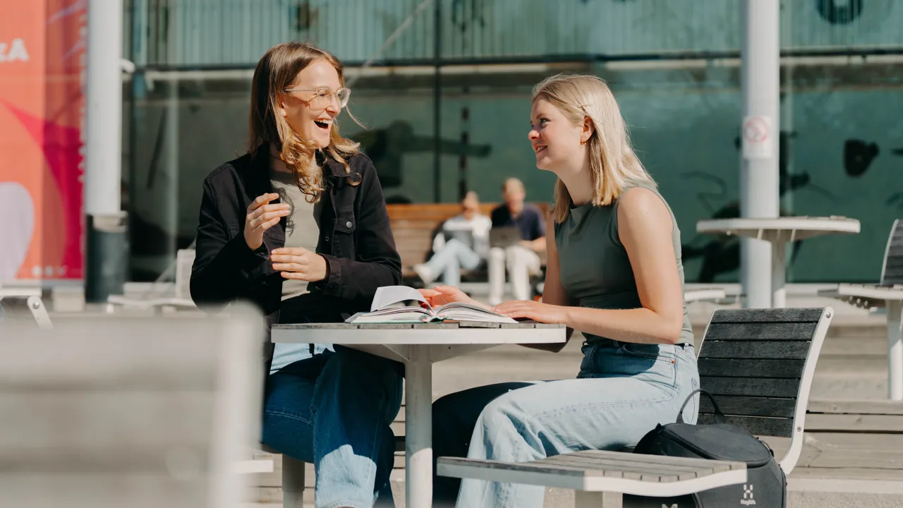 Två personer sitter vid ett bord och pratar och skrattar.