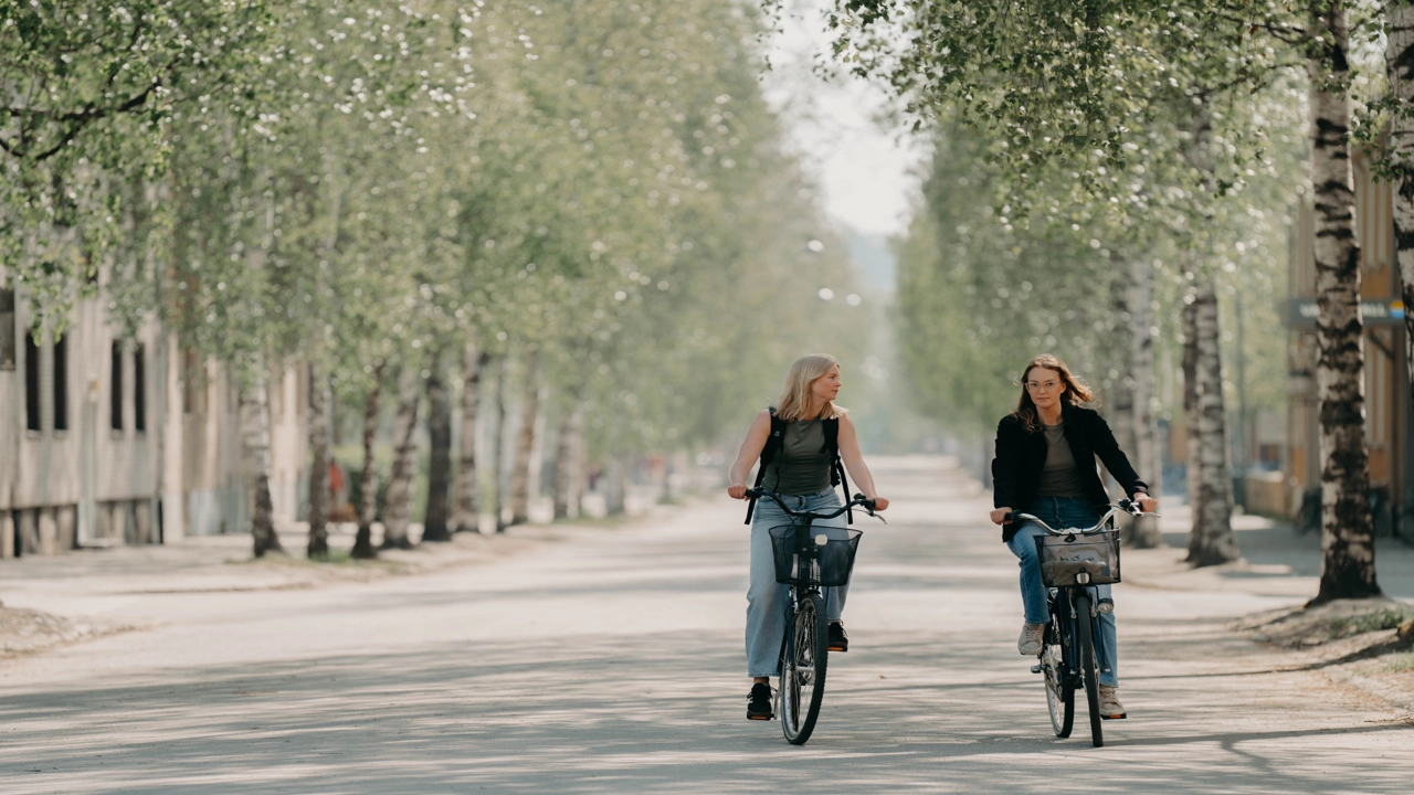 Två kvinnor cyklar bredvid varandra.