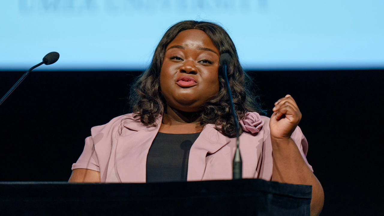 Student speaking at a graduation ceremony in front of a podium.