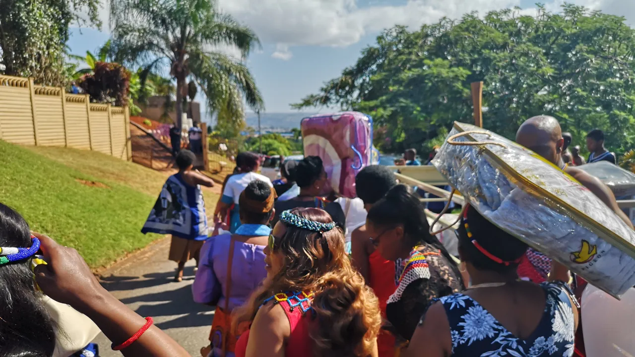 En grupp färgglatt klädda kvinnor går i grupp i en solig miljö med palmer.