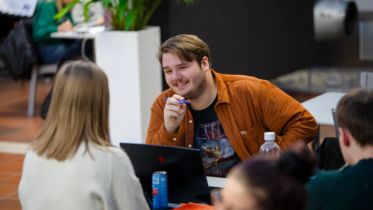 En glad student pluggar tillsammans med andra i Teknikhuset