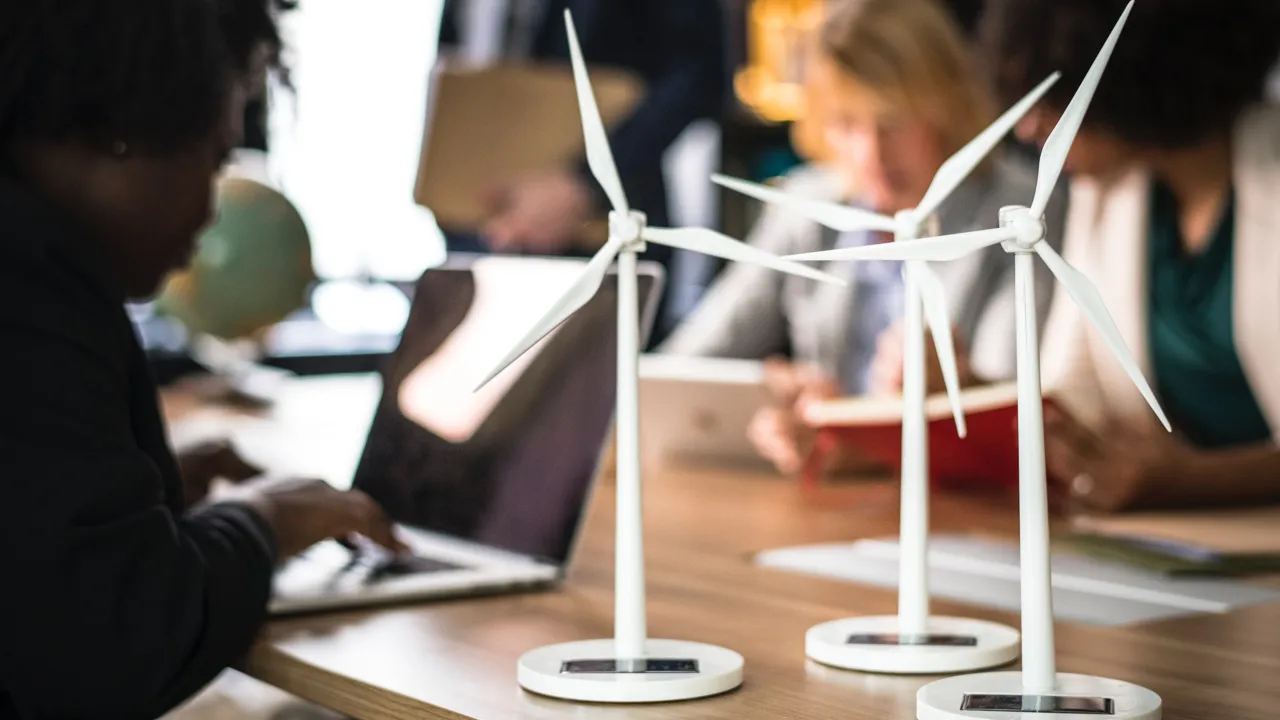 Miniatyrvindkraftverk står på ett skrivbord bredvid datorer.