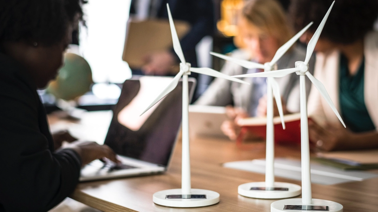 Miniature wind turbines sit on a desk next to computers.