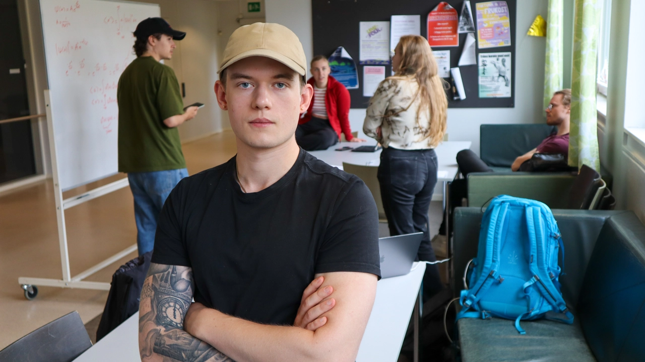 Porträtt på Theodor Ringius, i bakgrunden studenter samlade kring en whiteboardtavla i korridoren