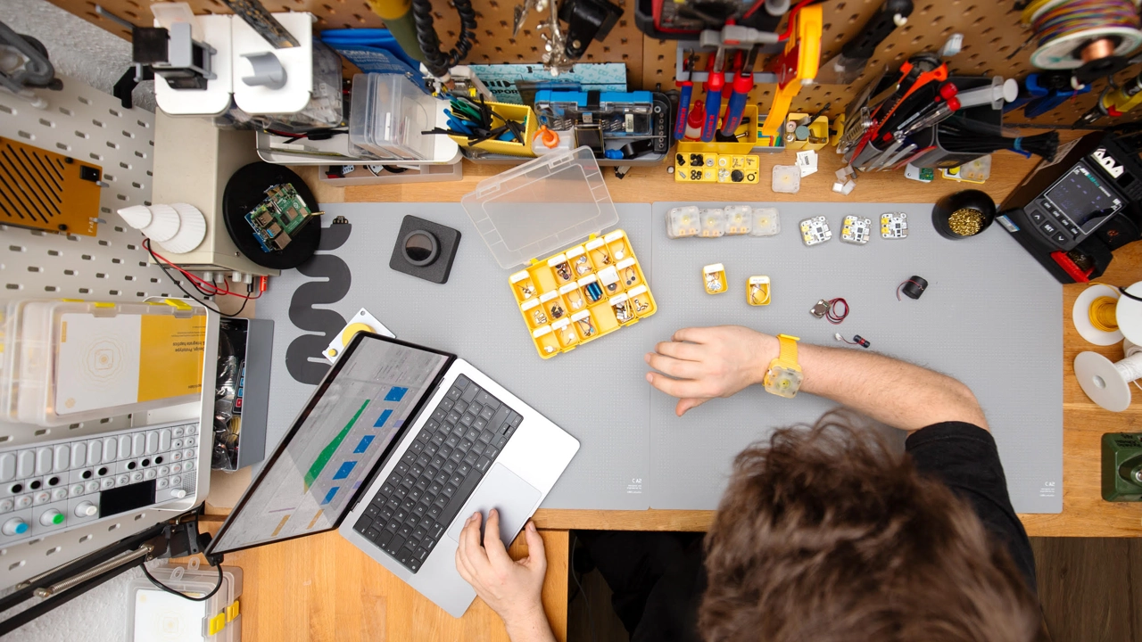 Foto av skrivbord med dator och prylar sett uppifrån