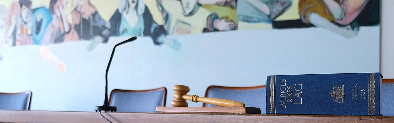 En blå lagbok som ligger på ett träbord med en domarklubba bredvid.