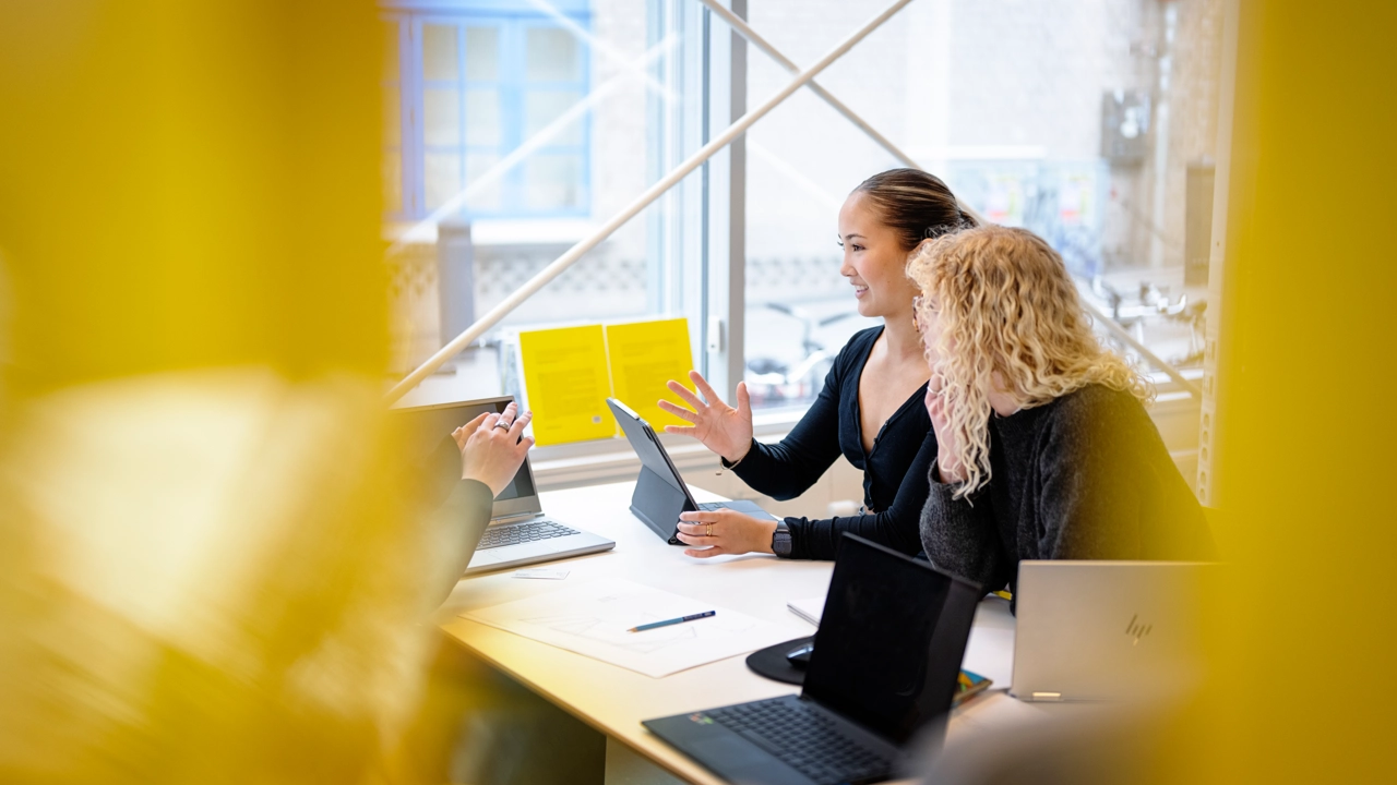 Two women in conversation in an office landscape.