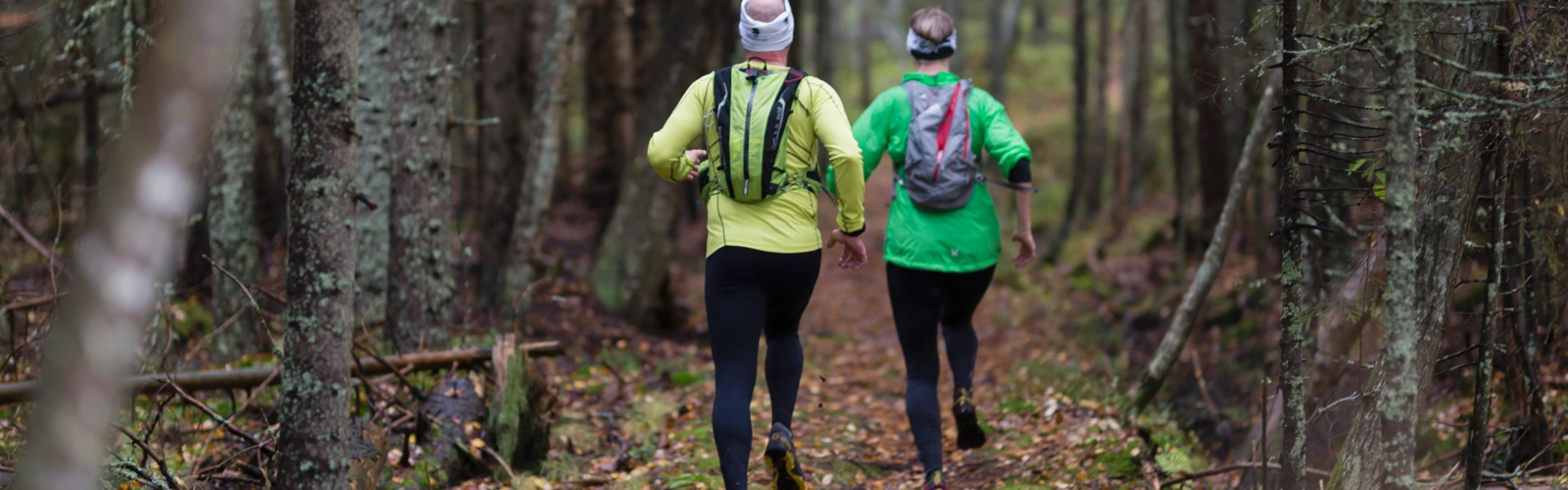 Två löpare i skogen på hösten