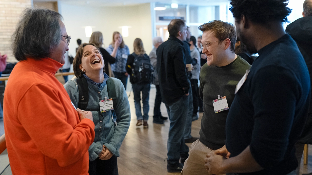 En grupp konferensdeltagare som skrattar med minglande människor i bakgrunden. 