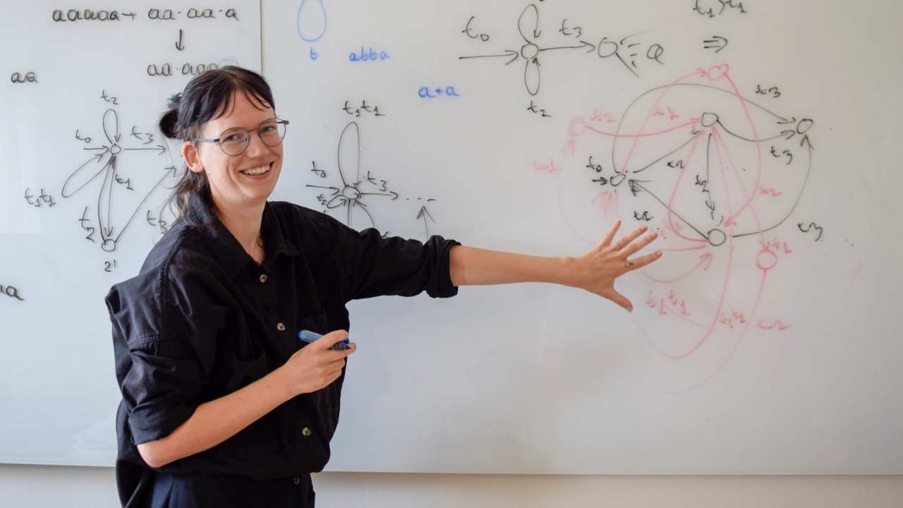 Bild på Willeke Martens vid whiteboardtavla med figurer och formler