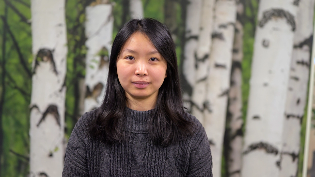 A woman standing in front of a painting of trees