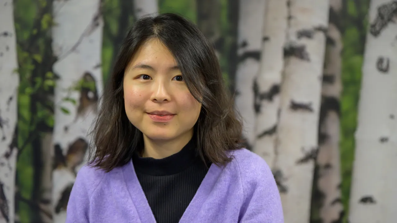 A woman standing in front of a painting of trees
