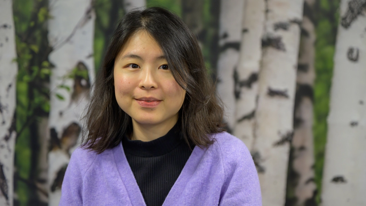 En kvinna står framför en målning med träd